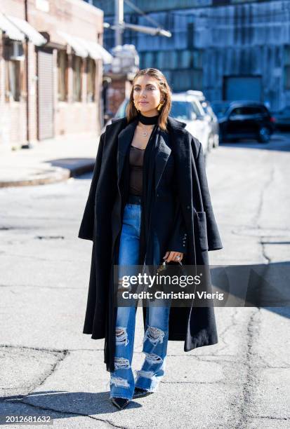 Campbell Puckett wears ripped denim jeans, black coat, bag outside Brandon Maxwell on February 14, 2024 in New York City.