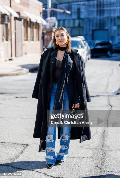 Campbell Puckett wears ripped denim jeans, black coat, bag outside Brandon Maxwell on February 14, 2024 in New York City.