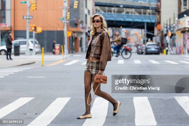 Millane Friesen wears brown Chanel bag, leather jacket, Miu Miu checkered shorts, tights, beige black shoes, sunglasses on February 14, 2024 in New...