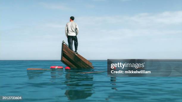 rowboat sinks in the middle of the sea and man looks for solution - sinking rowboat stock pictures, royalty-free photos & images