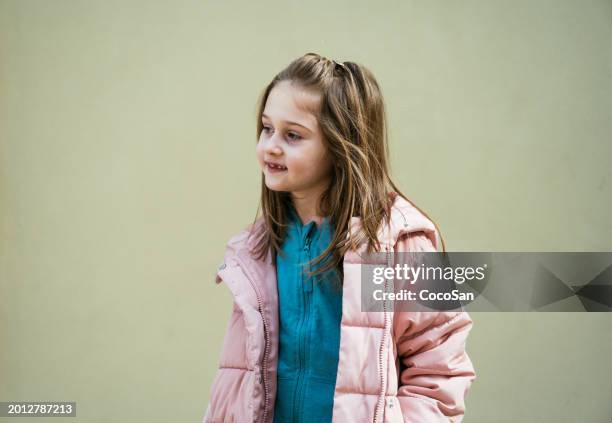 linda niña de siete años posando contra la pared pastel - coco girls fotografías e imágenes de stock