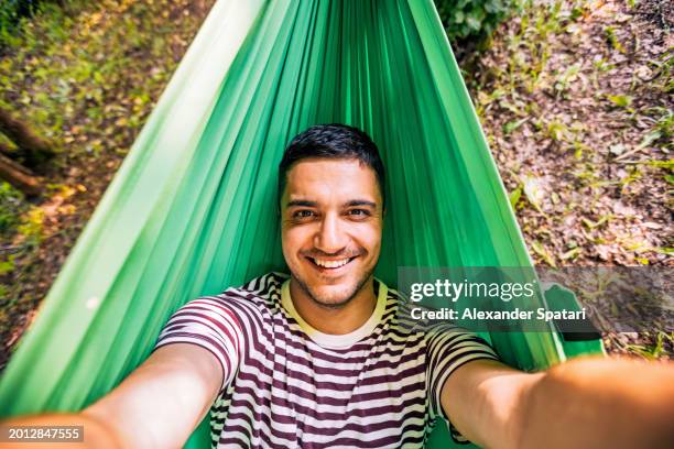 happy smiling man taking selfie while relaxing in the hammock - transylvania stock pictures, royalty-free photos & images