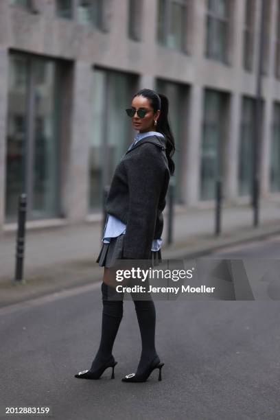 Tara Tut seen wearing Dior black sunglasses, gold earrings, Dior light blue cotton buttoned blouse shirt, H&M grey wool knit zip sweater, Arket dark...