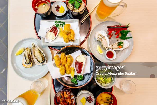 variation of oysters on the table in restaurant, high angle view, miyajima, japan - miyajima stock pictures, royalty-free photos & images