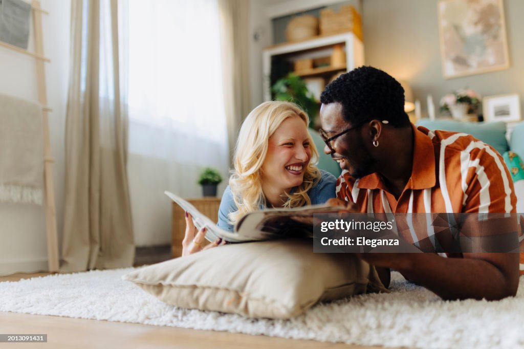 Young couple reading magazines. They are talking and sharing some laughs.
