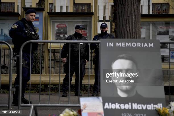 Police take security measures as people lay flowers and light candles next to the posters of Russian opposition figure Alexey Navalny after he died...