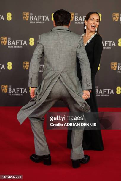 Actor Robert Downey Jr dances whilst US film producer Susan Downey reacts on the red carpet upon arrival at the BAFTA British Academy Film Awards at...