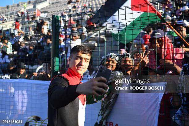 Palestinian national football team's Yazan Sharha uses a mobile phone to take a picture with supporters during an exhibition football match between...