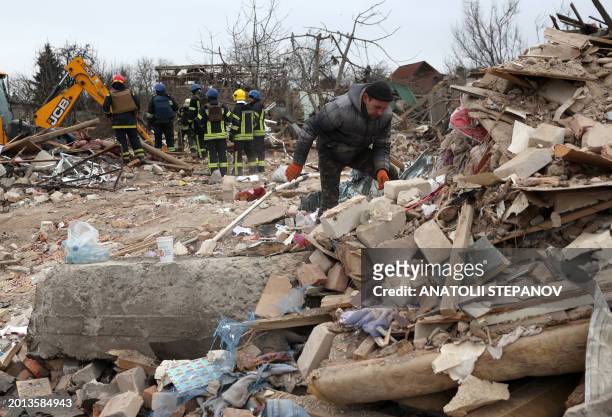 Relatives look for personal belongings of a deceased family amid the rubble of a house which was destroyed by a missile attack in the town of...