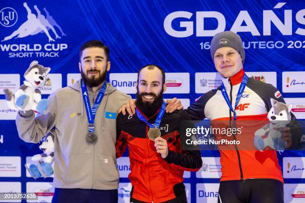 Denis Nikisha, Steven Dubois, and Michal Niewinski are posing on the podium during the men's medal ceremony after competing in the final 500m men's...