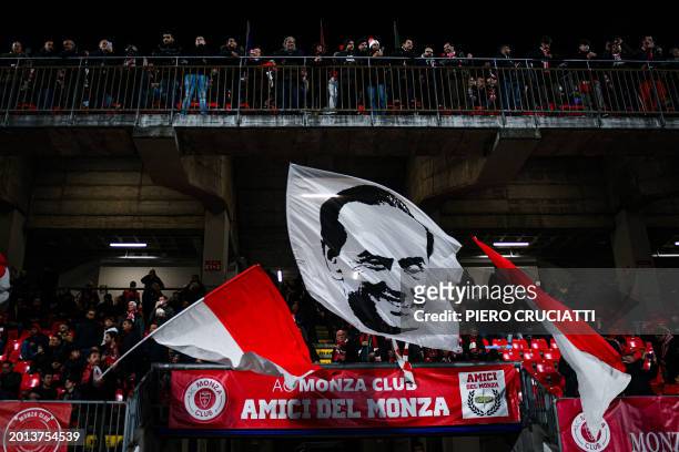 Monza supporters wave a flag depicting former Italian President Silvio Berlusconi ahead of the Italian Serie A football match between AC Monza and AC...