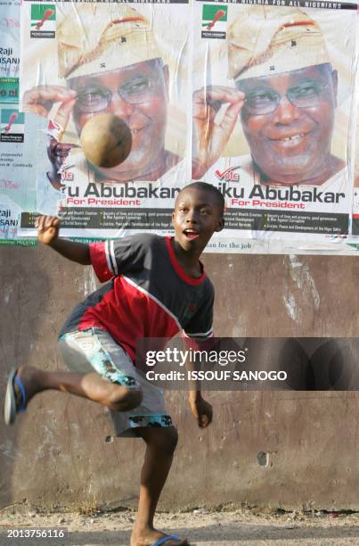 Child plays with a ball backdropped by posters of presidential candidate Atiku Abubacar 21 April 2007 in Lagos on the first day of polling to choose...