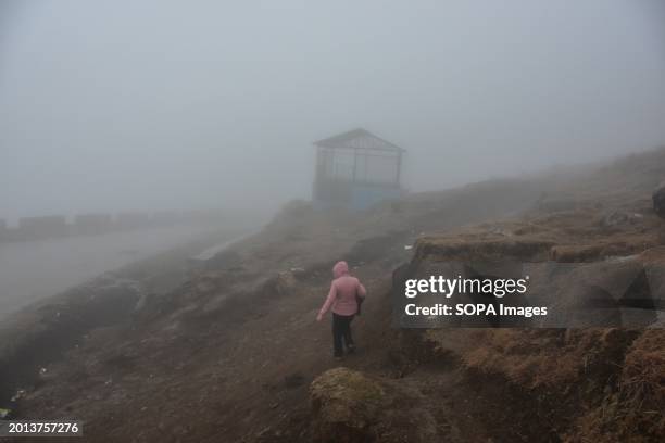 Woman walks down the hill during a rainy day and fog on the outskirts of Srinagar, the summer capital of Jammu and Kashmir.