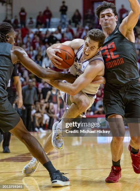 Ryan Langborg of the Northwestern Wildcats dribbles against Trey Galloway and Mackenzie Mgbako of the Indiana Hoosiers during the second half at...