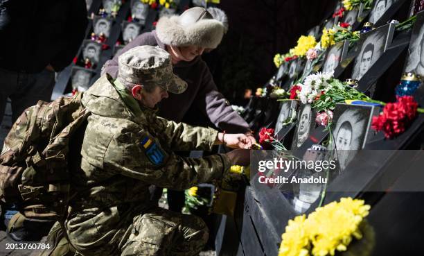 People place flowers as Kyiv residents attend a memorial service to commemorate protesters killed during the Revolution of Dignity in 2014 in Kyiv,...