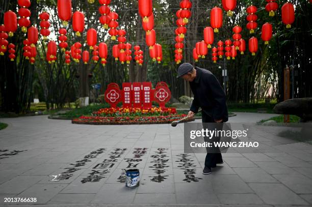 An elderly man writes Chinese characters on the ground with a brush at a park in Chengdu, China's Sichuan province on February 19, 2024.
