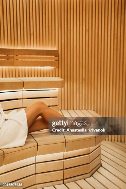 long legged woman wrapped in white towel in a traditional sauna. - cipresso stock-fotos und bilder