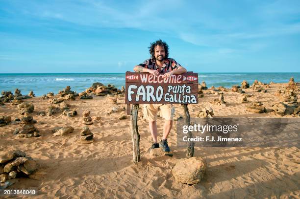 man standing next to punta gallinas lighthouse sign, la guajira, colombia - gallinas stock pictures, royalty-free photos & images