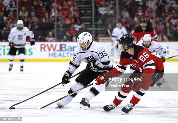 Viktor Arvidsson of the Los Angeles Kings takes the puck as Jack Hughes of the New Jersey Devils defends during the third period at Prudential Center...