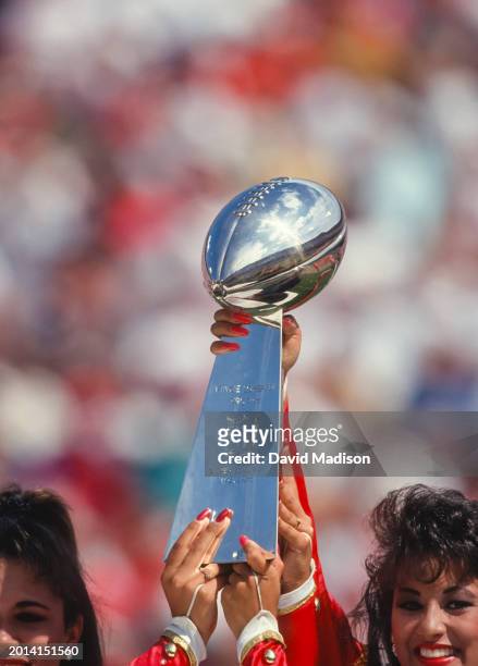 The Vince Lombardi Trophy for Super Bowl XIX is held aloft by two cheerleaders during a National Football League game between the San Francisco 49ers...