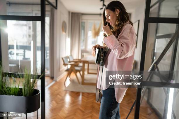 woman checking purse before leaving home - woman looking in handbag stock pictures, royalty-free photos & images
