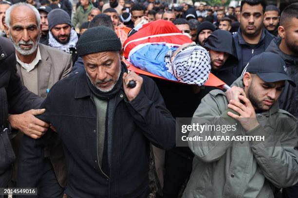 Palestinian mourners carry the body of Nabil Mohammed Amer during his funeral at the Tulkarm camp for Palestinian refugees on February 19 a day after...