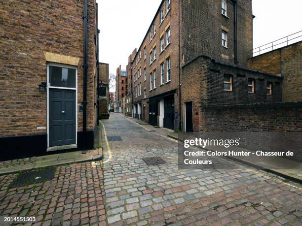 a narrow, cobbled street in a mews in london, england, united kingdom. weathered brick walls and facades with doors and windows. no people. day light. natural colors. - cobblestone floor stock pictures, royalty-free photos & images