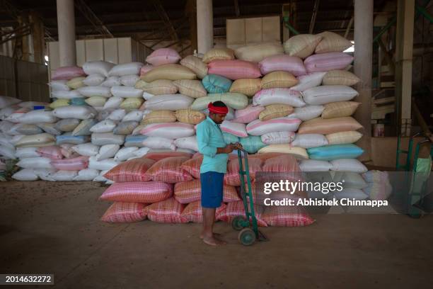 Akilesh Yadav, a migrant worker from Motihari, Bihar waits to load a weighed sack of coffee inside a coffee curing works plant on January 20, 2024 in...