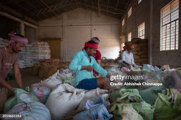 Migrant workers from the northern states of Uttar Pradesh and Bihar sew sacks of coffee inside a coffee curing works plant on January 20, 2024 in...