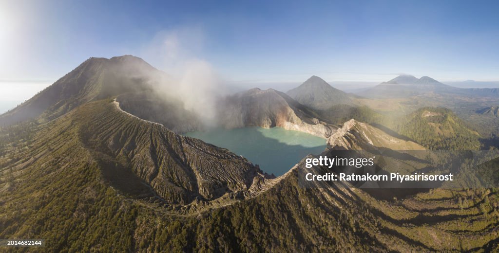 Aerial view flying around mount Kawah Ijen crater with Smoke on crater and turquoise lake, Sulfur mining in an active volcano, Java, Indonesia