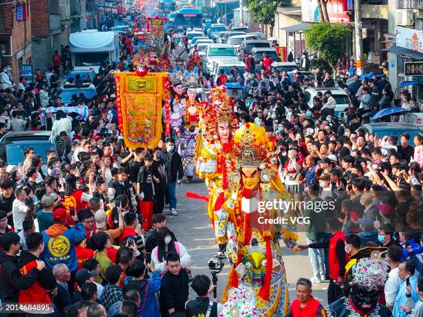 Local people carrying statues of deities parade on the street as they attend the traditional Lunar New Year customs known as 'Youshen' or 'Wandering...