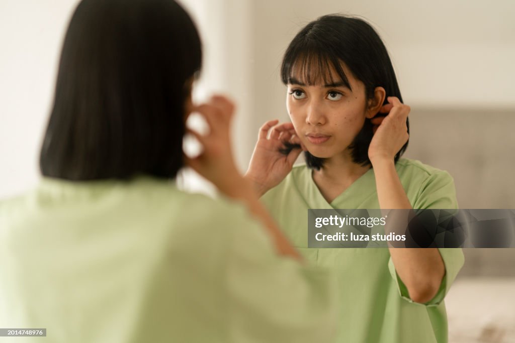 Woman looking at herself in the mirror, fixing her hair