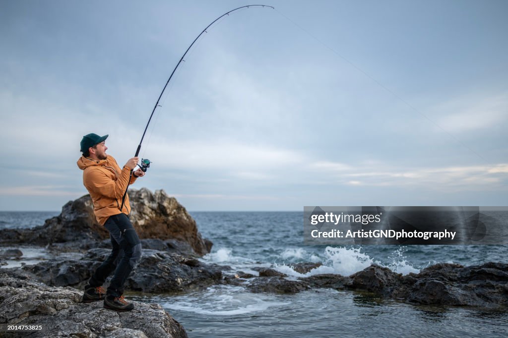 Fisherman pulling the rod after catching a fish. I catch it!