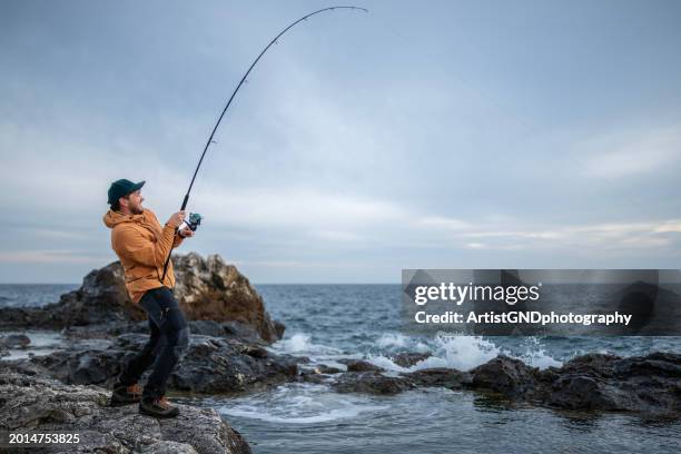 fisherman pulling the rod after catching a fish. i catch it! - fishing rod stock pictures, royalty-free photos & images