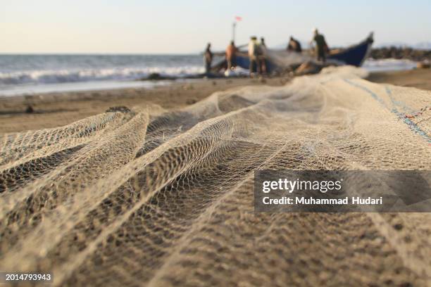 javanese fishermen clean nets on banda aceh's coast - fishing net stock pictures, royalty-free photos & images
