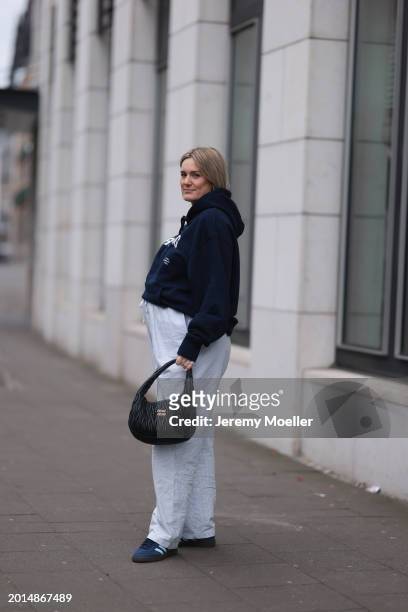 Victoria Thomas seen wearing gold earrings, Hernameis navy blue oversized cotton logo pattern hooded sweater, Hernameis white / blue striped long...