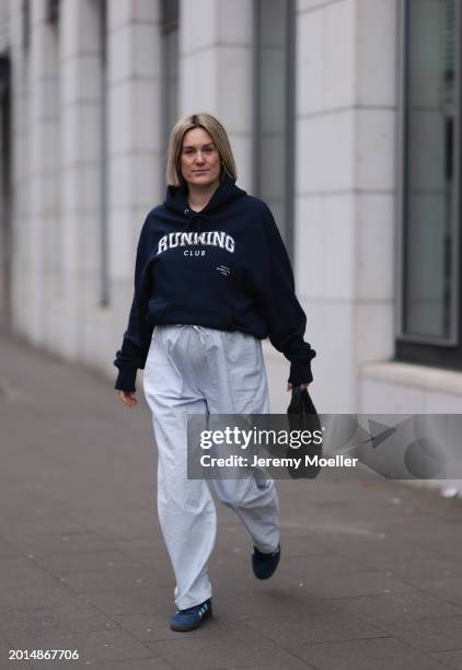 Victoria Thomas seen wearing gold earrings, Hernameis navy blue oversized cotton logo pattern hooded sweater, Hernameis white / blue striped long...