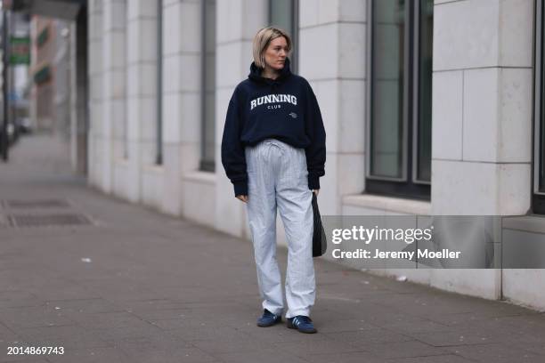 Victoria Thomas seen wearing gold earrings, Hernameis navy blue oversized cotton logo pattern hooded sweater, Hernameis white / blue striped long...