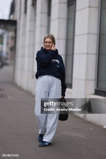 Victoria Thomas seen wearing gold earrings, Hernameis navy blue oversized cotton logo pattern hooded sweater, Hernameis white / blue striped long...