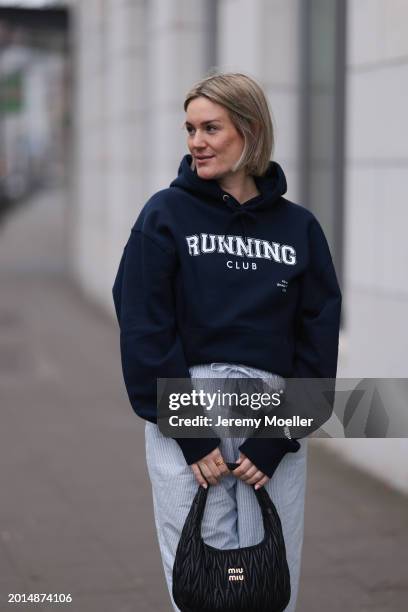 Victoria Thomas seen wearing gold earrings, Hernameis navy blue oversized cotton logo pattern hooded sweater, Hernameis white / blue striped long...