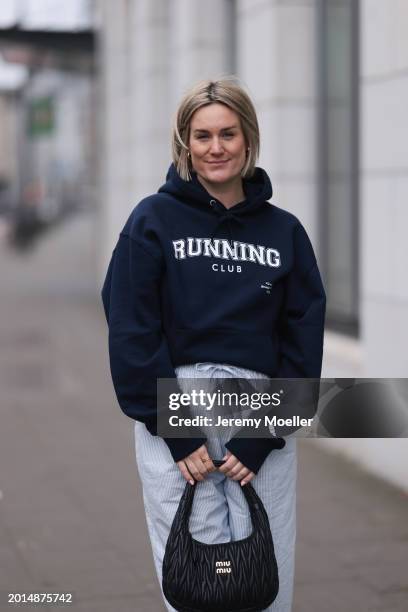 Victoria Thomas seen wearing gold earrings, Hernameis navy blue oversized cotton logo pattern hooded sweater, Hernameis white / blue striped long...