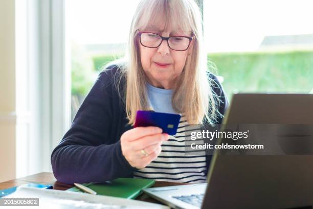 seniorin, die online-zahlungen mit kreditkarte und laptop tätigt - wirtschaftskriminalität stock-fotos und bilder