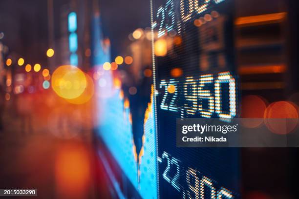 unscharfe urbane nachtlandschaft mit beleuchtetem digitalen börsenticker - market stock-fotos und bilder