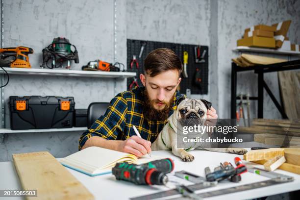 repairman takes notes while holds pug in lap - pug stock pictures, royalty-free photos & images