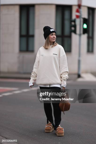 Elise Rozay seen wearing gold earrings, Hernameis black wool knit logo patch beanie, Hernameis creamy white logo print pattern oversized sweater,...