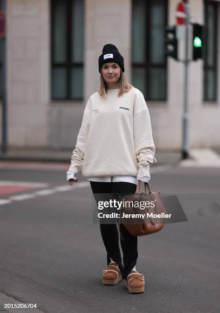 Elise Rozay seen wearing gold earrings, Hernameis black wool knit logo patch beanie, Hernameis creamy white logo print pattern oversized sweater,...