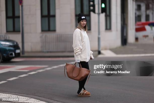 Elise Rozay seen wearing gold earrings, Hernameis black wool knit logo patch beanie, Hernameis creamy white logo print pattern oversized sweater,...