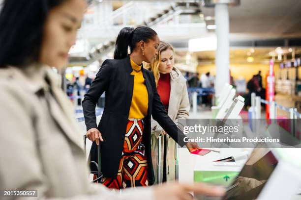 women using self check-in kiosks at the airport - self service stock pictures, royalty-free photos & images