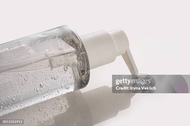 moisturizing transparent cosmetic drop of gel or serum, cosmetic water, micellar water, collagen, face cleaning gel pours out from white bottle with oxygen aqua bubbles on white gray color background. - soap dispenser stock pictures, royalty-free photos & images