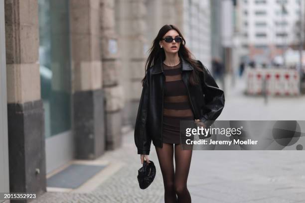 Celine Bethmann seen wearing Chanel vintage black oval sunglasses, Dior gold earrings, Norma Kamali brown / transparent striped short dress, Wolford...